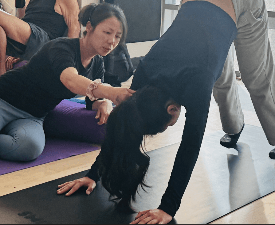 Ashley assisting a student with downward facing dog